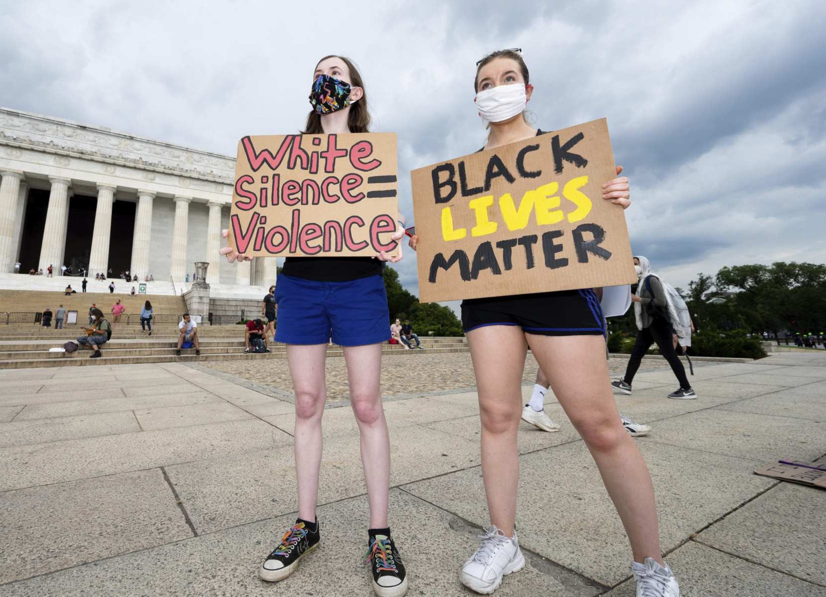 Two women stand with anti-racist signs.