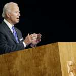 Joe Biden stands at a lecturn.