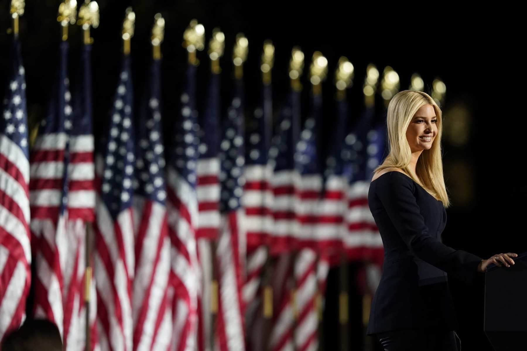 Ivanka Trump giving a speech in front of a row of American flags.
