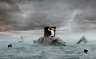 A composite illustration of a woman trapped in a box with stormy seas surrounding her.