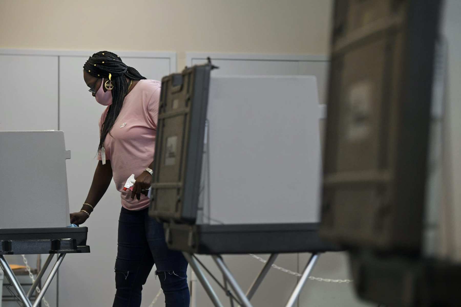 A woman cleans a voting booth.