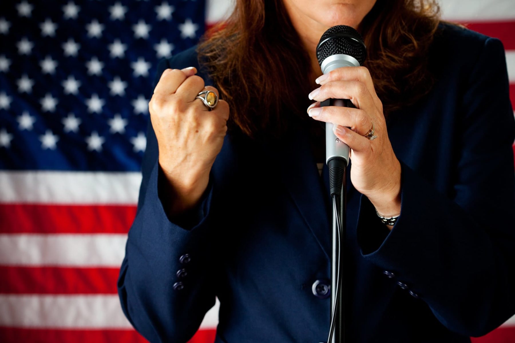 A woman candidate standing in front of an American flag.