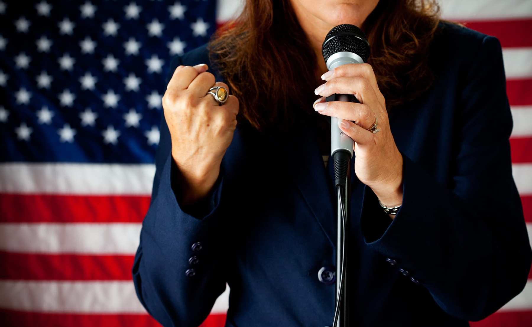 A woman candidate standing in front of an American flag.