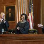 In this March 7, 2019 file photo, Associate Justices Paul Newby and Robin Hudson applaud for new Chief Justice Cheri Beasley, center, of the N.C. Supreme Court during Beasley's investiture ceremony in Raleigh. In North Carolina's Supreme Court chamber, above the seat held by Beasley, the second African American chief justice, hangs a towering painting of Chief Justice Thomas Ruffin, a 19th century slave owner and jurist who authored a notorious opinion about the “absolute” rights of slaveholders over the enslaved. In October 2018 the state Supreme Court named a commission to review the portraits in the building that houses the court ,including Ruffin's.  (Paul Woolverton/The Fayetteville Observer via AP)