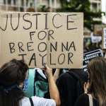 A girl holding a cardboard sign asking justice for Breonna Taylor demonstrating in Mestre, Venice, Italy on June 6, 2020, to protest the killing of George Floyd by a policeman in the USA.