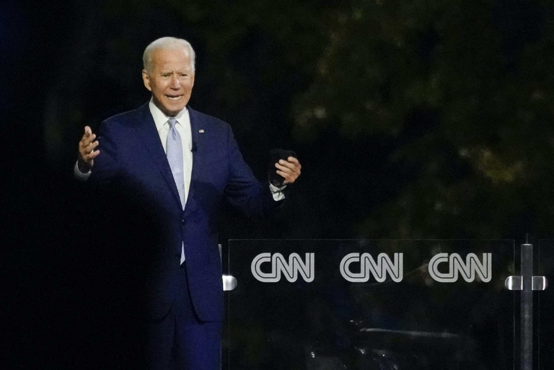 Joe Biden speaks to a crowd from a stage at a town hall event.