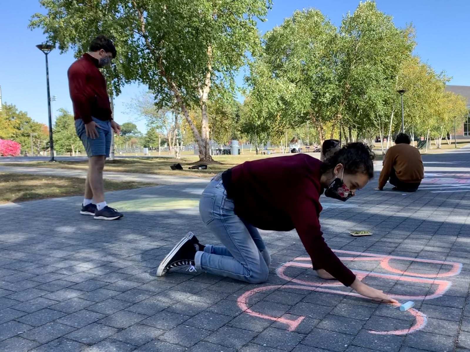 Olivia Eaton, a student majoring in classical medieval studies and minoring in gender studies at Bates College, on Saturday crafts a sidewalk chalk mural on the campus in Lewiston, Maine, honoring U.S. Supreme Court Justice Ruth Bader Ginsburg after her death the day prior.
