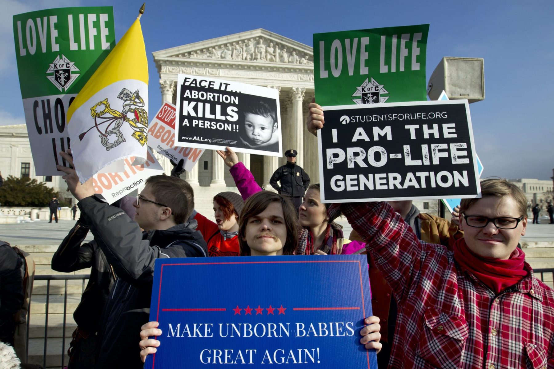 A group of protesters standing outside of the Supreme Court holding anti-abortion signs.