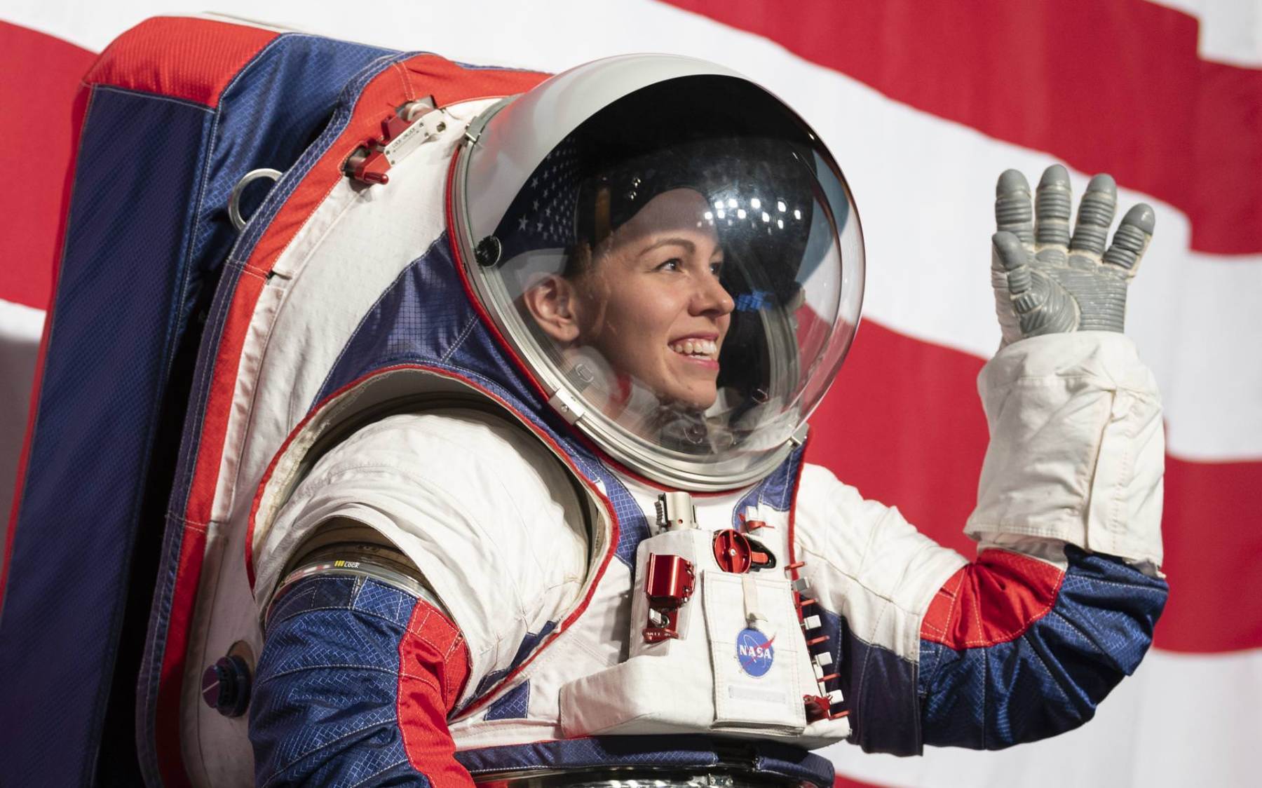 Kristine Davis, a spacesuit engineer at NASA’s Johnson Space Center, wearing a ground prototype of NASA’s new Exploration Extravehicular Mobility Unit (xEMU), pictured here waving and smiling during a demonstration of the suit, Tuesday, Oct. 15, 2019 at NASA Headquarters in Washington.