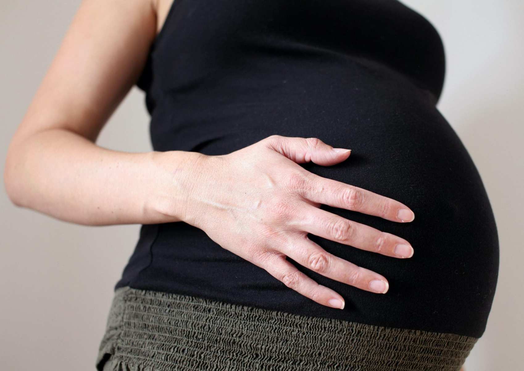 A pregnant woman puts her hand on her belly.