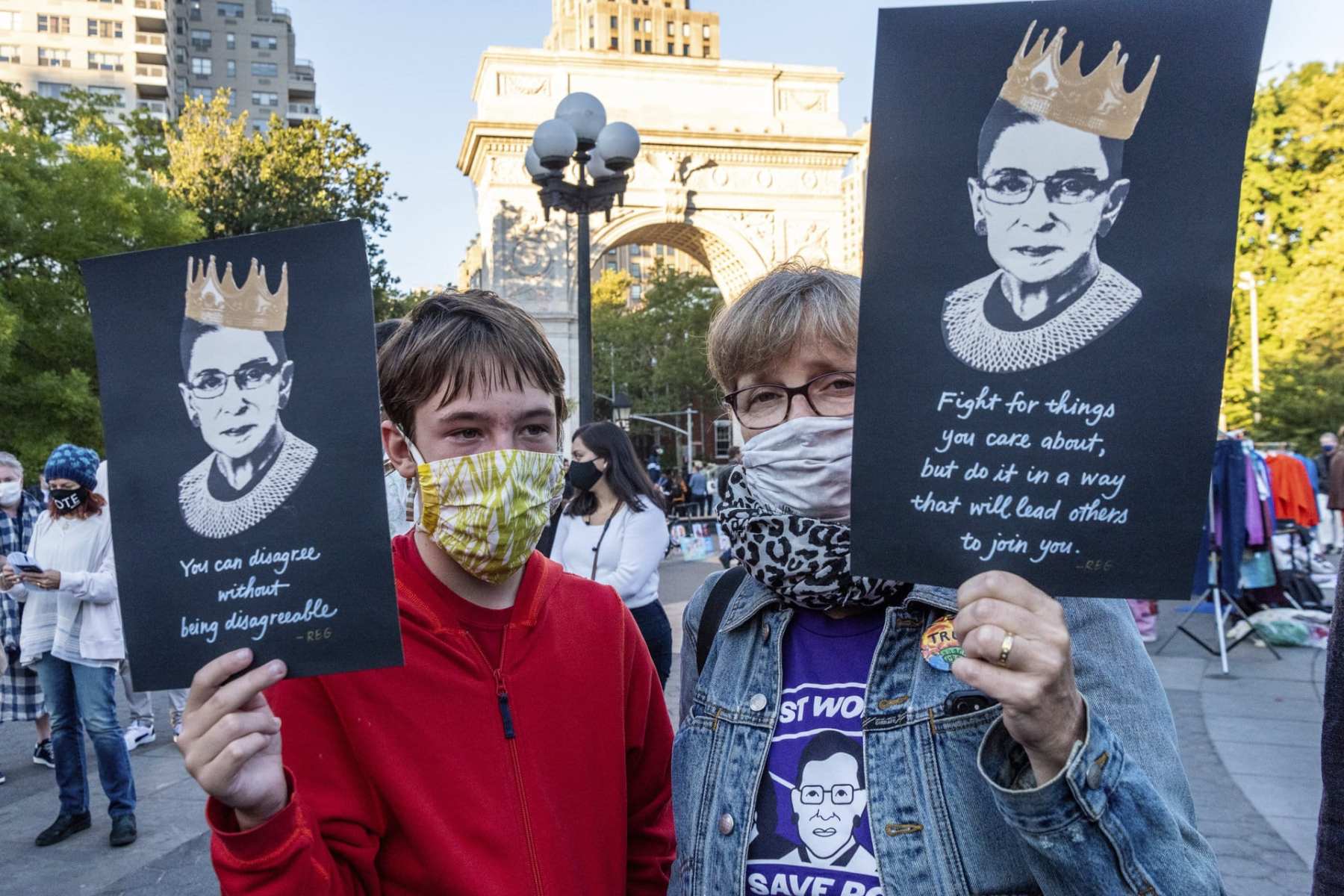 Two people carrying signs with Ruth Bader Ginsburg's face on them.
