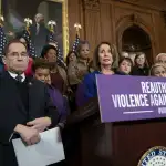 Nancy Pelosi and other legislators stand at a podium that reads 