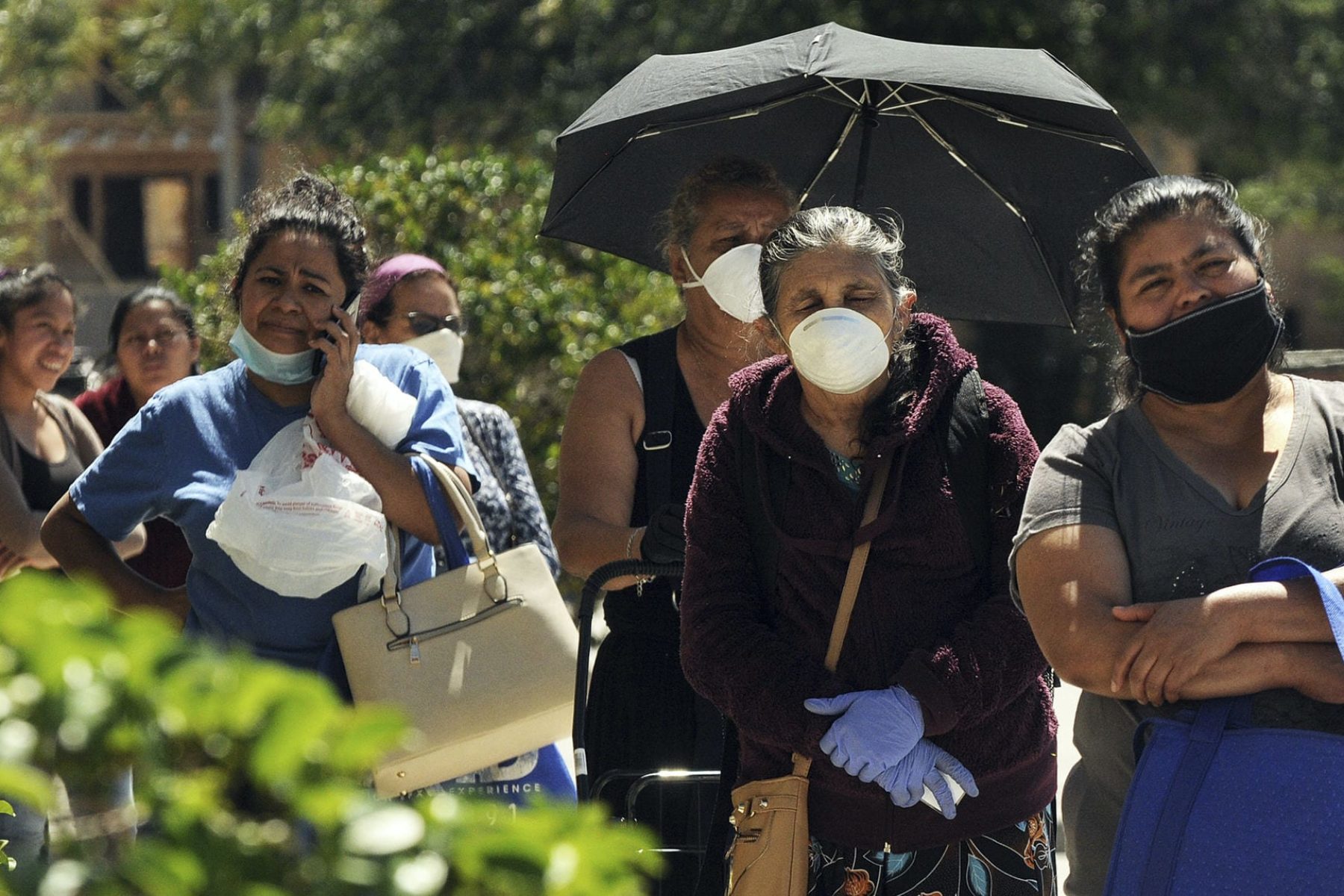 Women wearing protective masks wait in a queue to receive food assistance provided by the Second Harvest Food Bank of Central Florida at a food distribution event staffed by volunteers at the Calvario City Church. Food banks across the United States are being overwhelmed due to the thousands of people who have lost their jobs due to the coronavirus (COVID-19) pandemic.