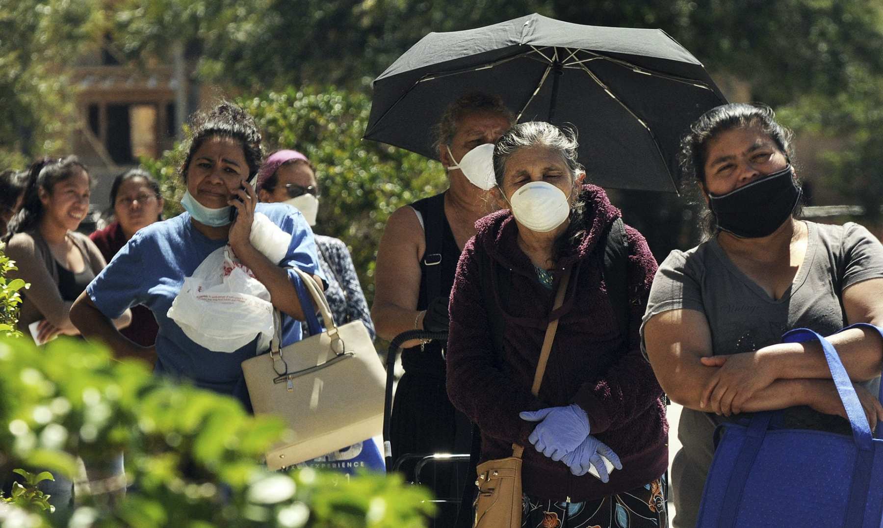 Women wearing protective masks wait in a queue to receive food assistance provided by the Second Harvest Food Bank of Central Florida at a food distribution event staffed by volunteers at the Calvario City Church. Food banks across the United States are being overwhelmed due to the thousands of people who have lost their jobs due to the coronavirus (COVID-19) pandemic.