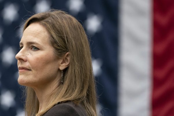 Amy Coney Barrett stands in front of the American flag.