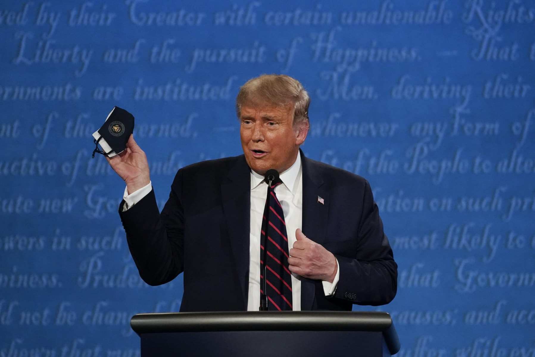 In this Sept. 29, 2020, file photo, President Donald Trump holds up his facemask during the first presidential debate at Case Western University and Cleveland Clinic, in Cleveland, Ohio. President Trump and first lady Melania Trump have tested positive for the coronavirus, the president tweeted early Friday. In this (AP Photo/Julio Cortez, File)