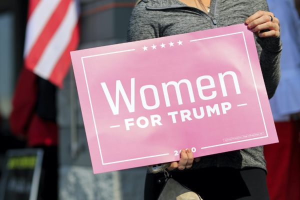 A voter holds a sign in support of Women For Trump outside the Hamilton County Board of Elections as people arrive to participate in early voting, Tuesday, Oct. 6, 2020, in Norwood, Ohio.