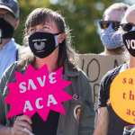 Protesters hold signs about the Affordable Care Act.