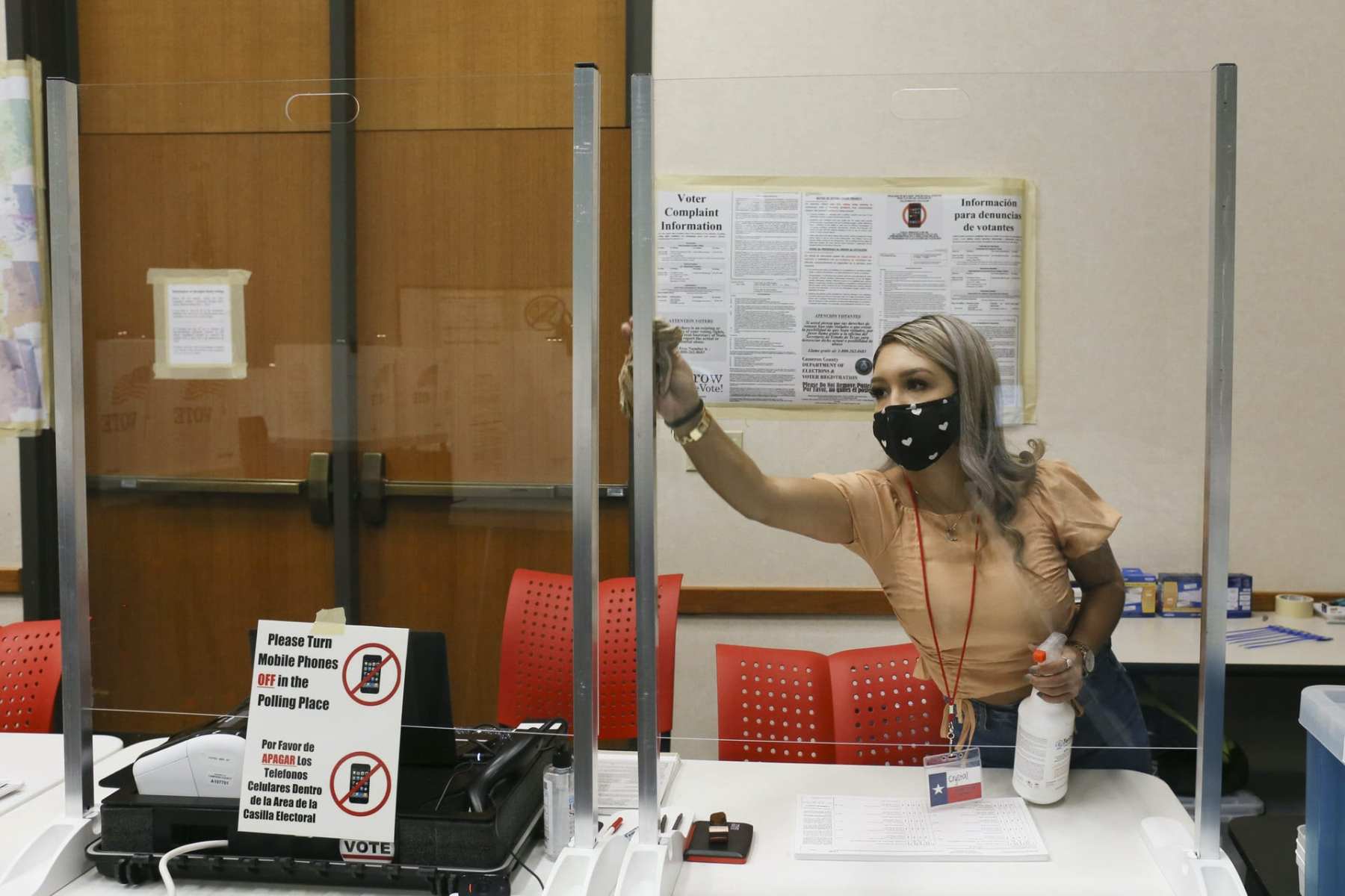A poll worker cleans a plexiglass barrier at a Texas polling place.