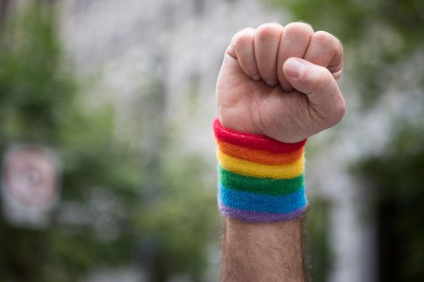 A fist raised in the air with a rainbow cuff.