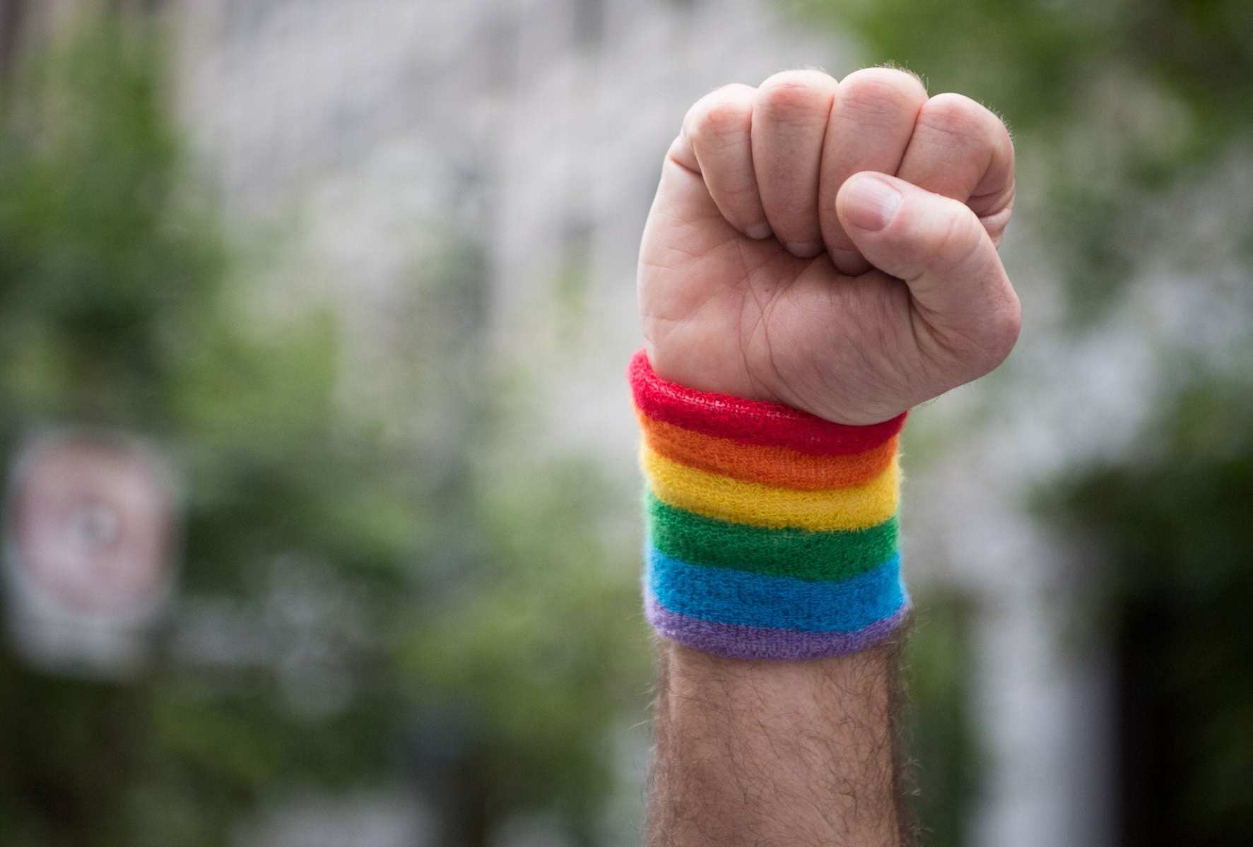 A fist raised in the air with a rainbow cuff.
