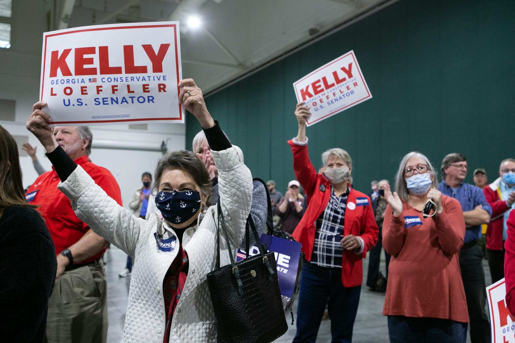 Supporters of Kelly Loeffler hold signs at a rally.