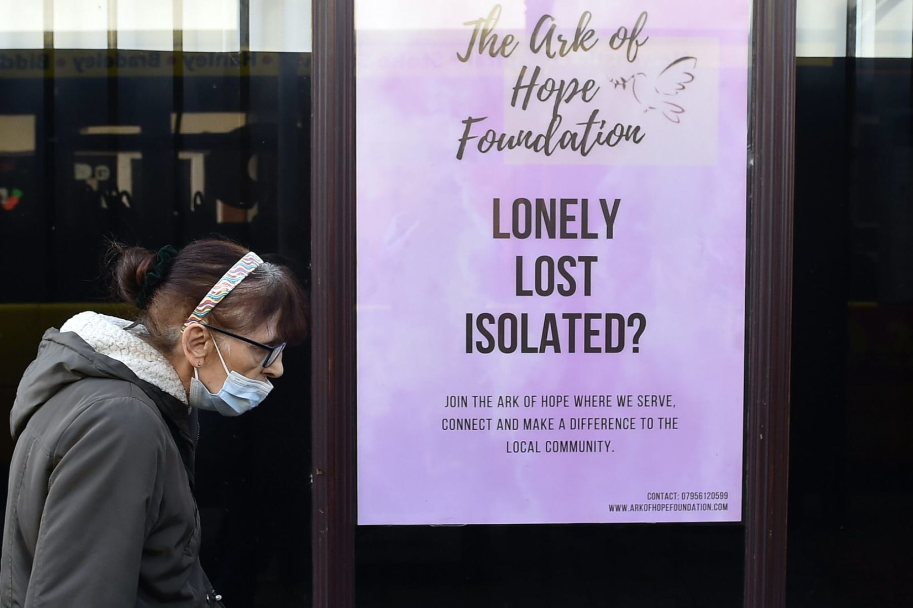 A woman wearing a mask walks past a sign that reads 