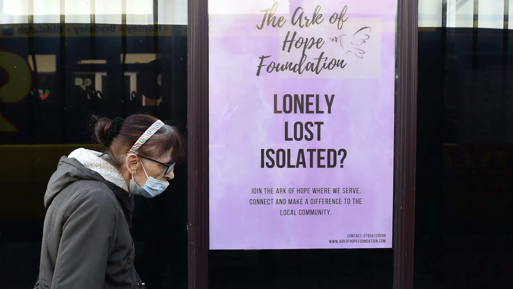 A woman wearing a mask walks past a sign that reads 