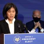 Katherine Tai delivers remarks from a podium with a masked Joe Biden standing behind her.