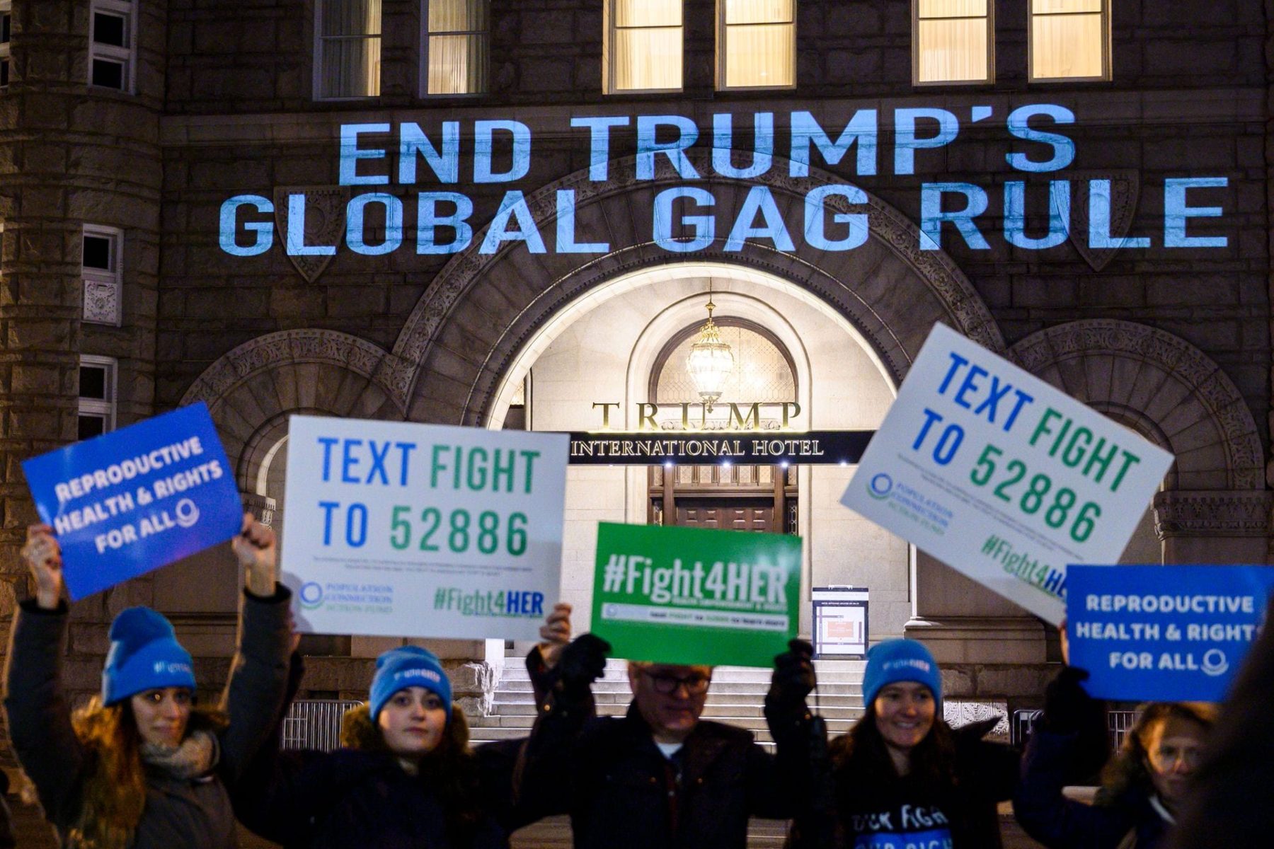 Activists from the Population Connection Action Fund hold signs in front of the Trump International Hotel..