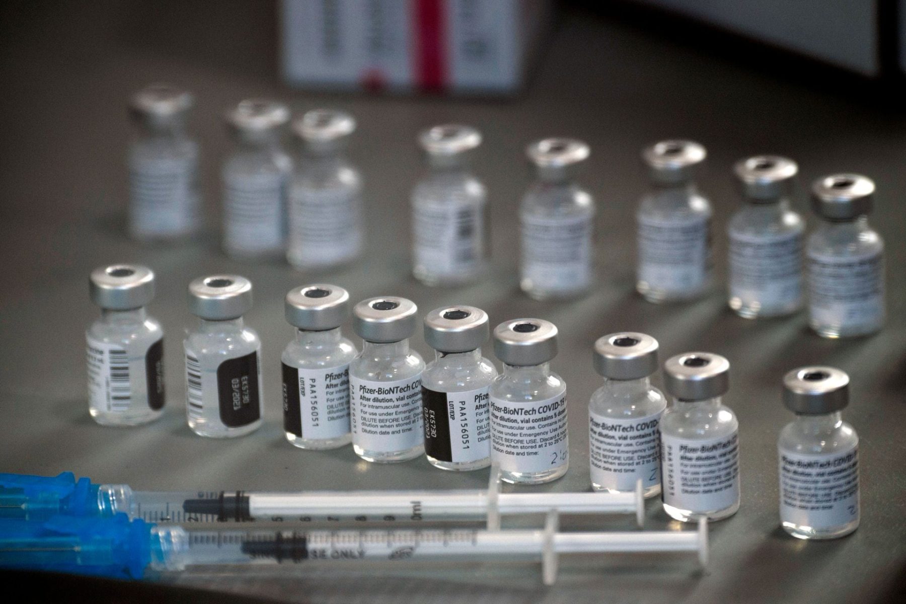 Close-up of syringes and vials of the Pfizer-BioNTech Covid-19 vaccine sitting on a table.