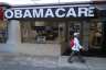 A woman walks past a lending agency with a large Obamacare sign.