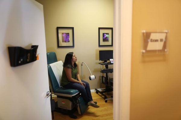 Natalia Reyes sits in the exam room as she gets a health care checkup.