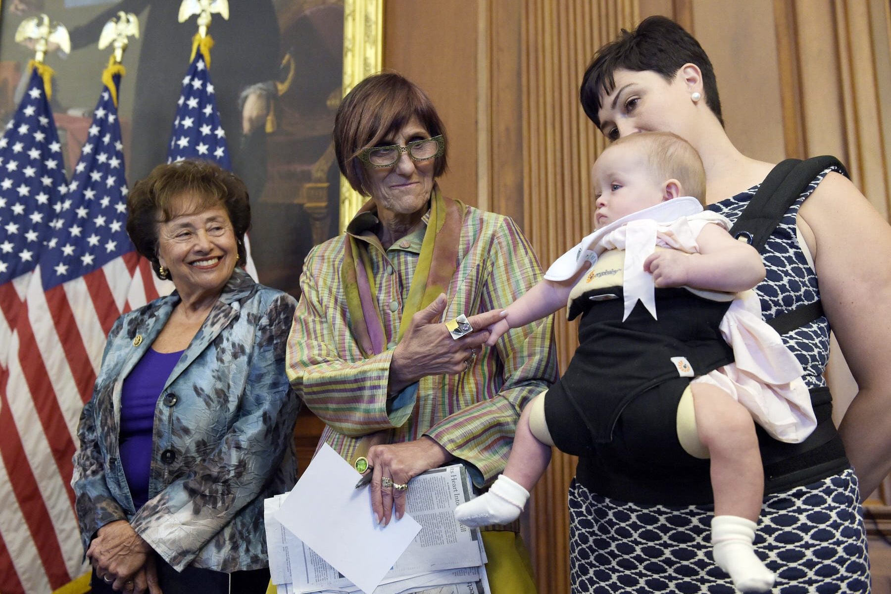 An image of Rep. Rosa DeLauro, D-N.Y. holding a baby's hand at a press conference., during a news conference.