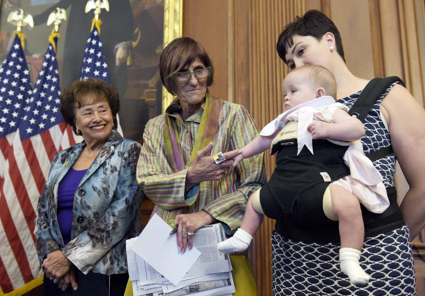 An image of Rep. Rosa DeLauro, D-N.Y. holding a baby's hand at a press conference., during a news conference.