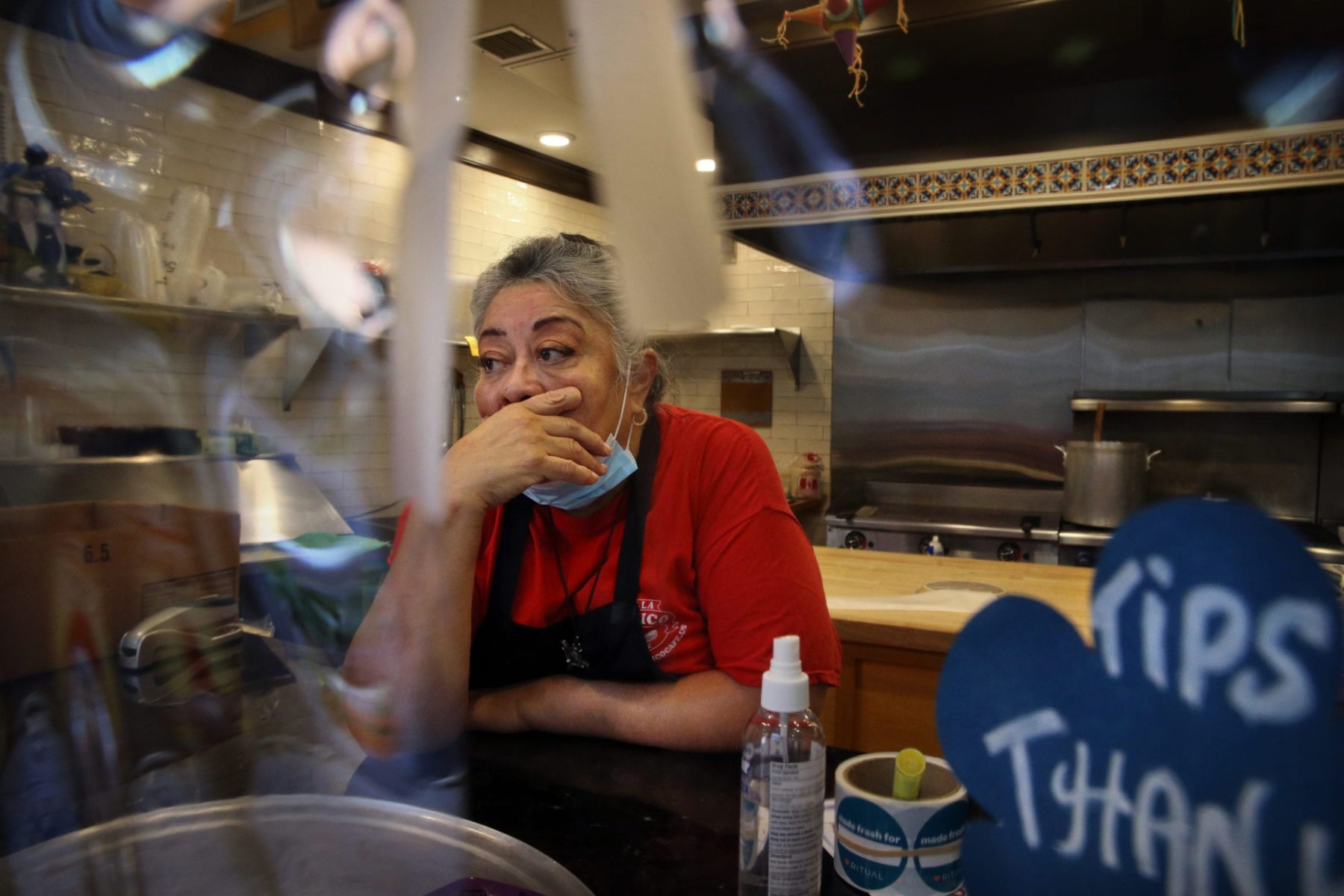Owner Julie King, in a red shirt covered by an apron, holds back tears at Villa Mexico Cafe on Water Street in Boston, MA. A customer had just walked out while she was on the phone with another customer who was trying to negotiate the price of an order. Having lost two customers in a matter of minutes she said, 