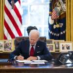 U.S. President Joe Biden signs a series of executive actions at his desk.
