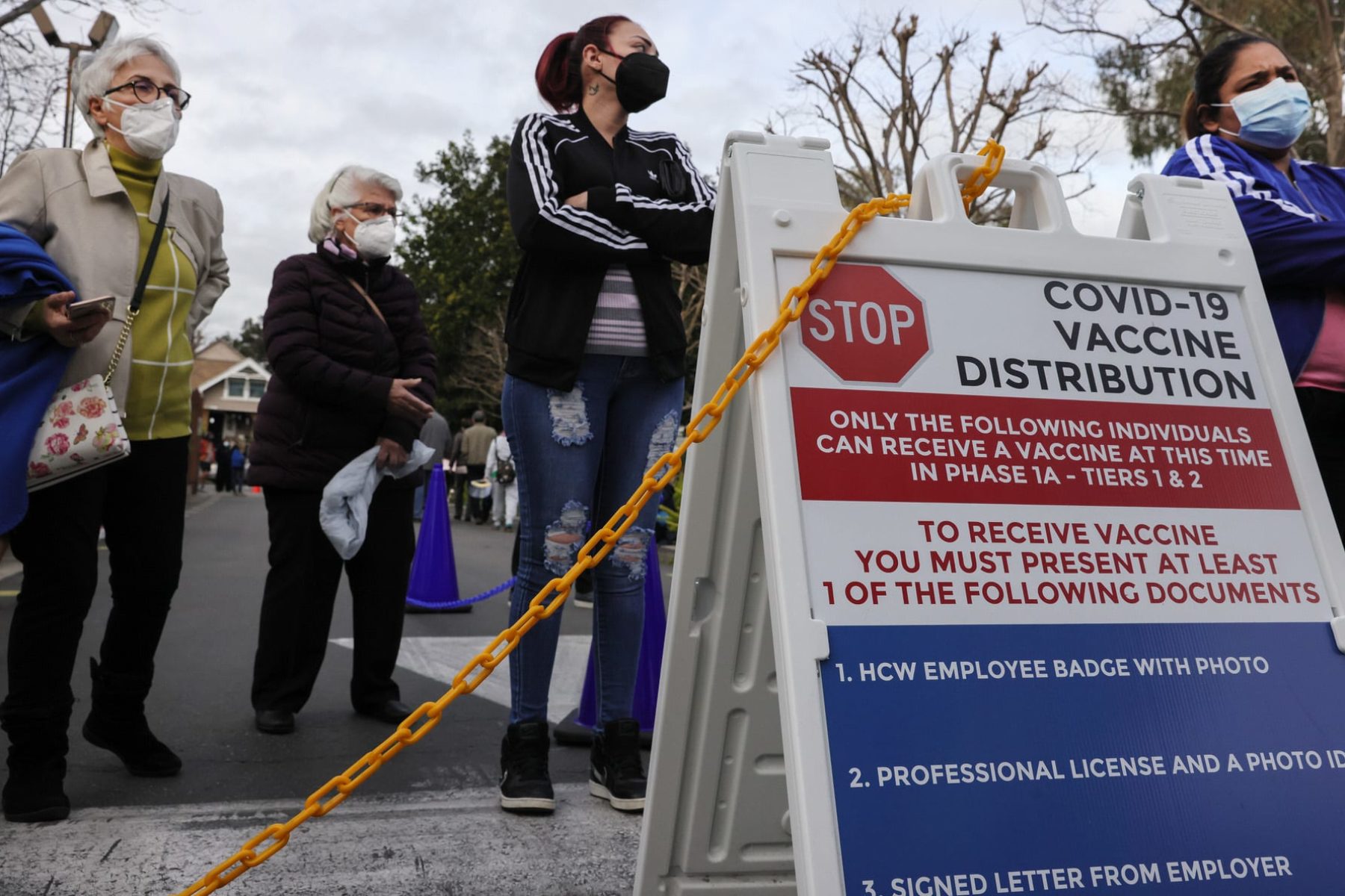 eople wait outside a COVID-19 vaccine distribution center.