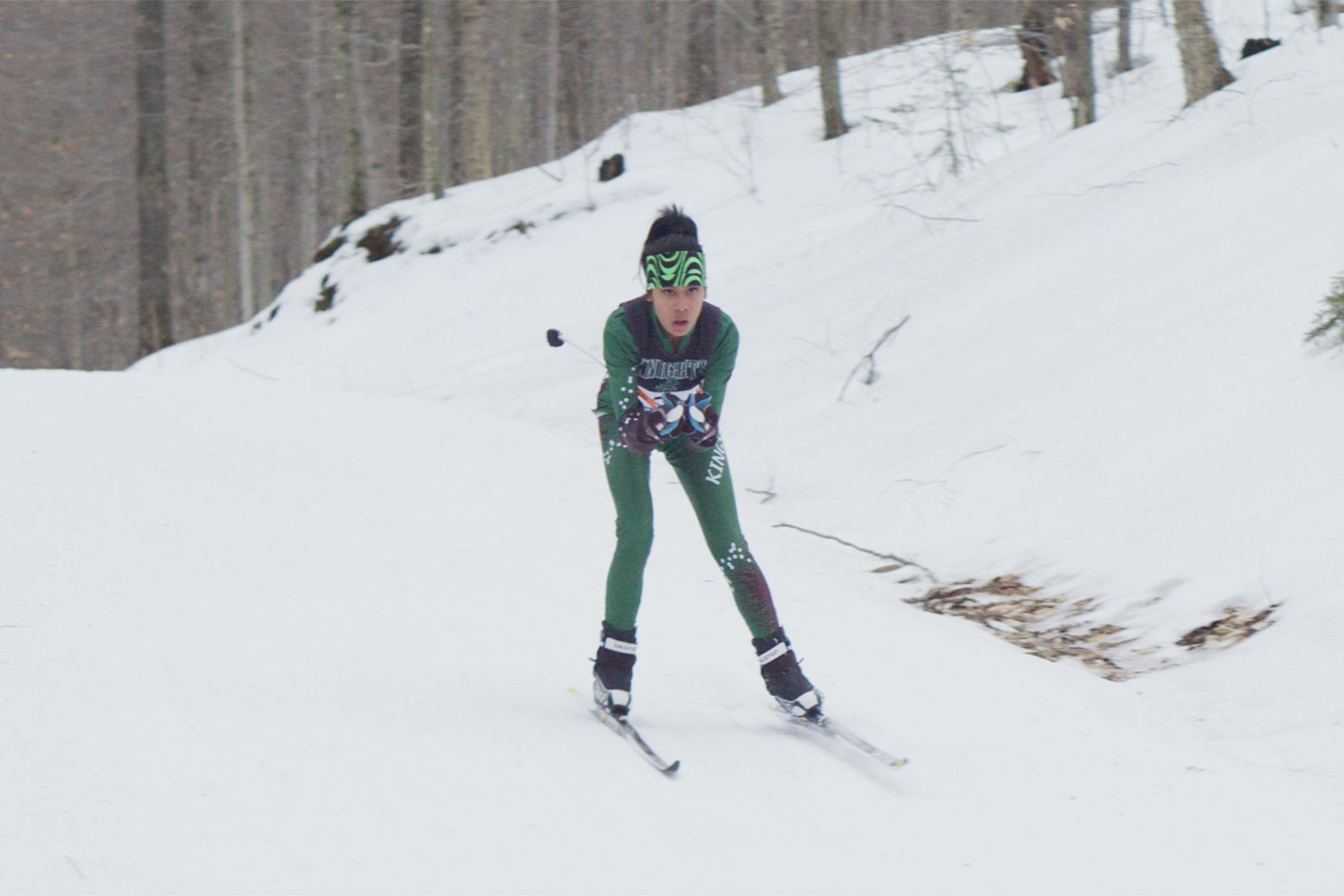 A girl skiing in a snowy forest.
