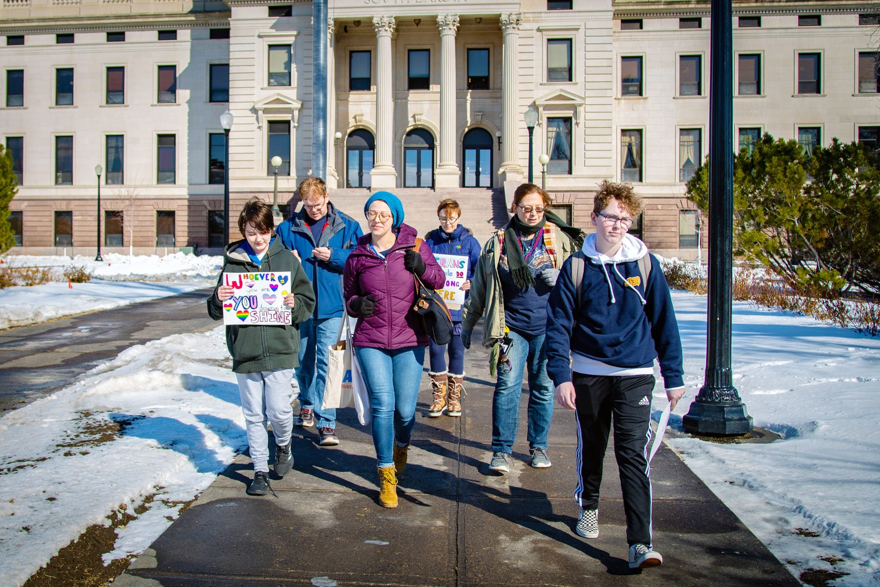 A group of trans youth walk in front of the South Dakota Capitol.