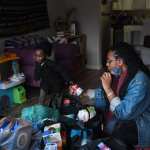 A woman looks at food and essential items as her child plays in the family room.
