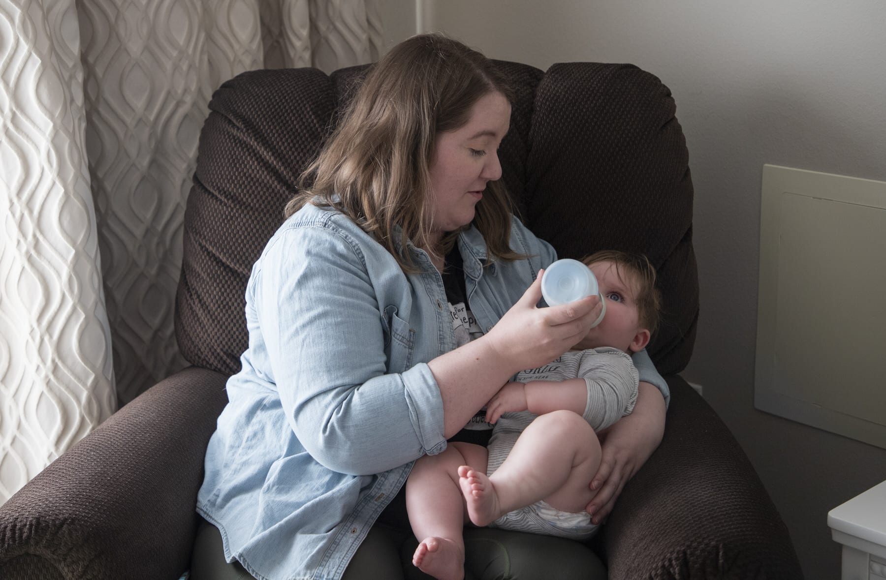 A mother feeds her baby a bottle of milk.