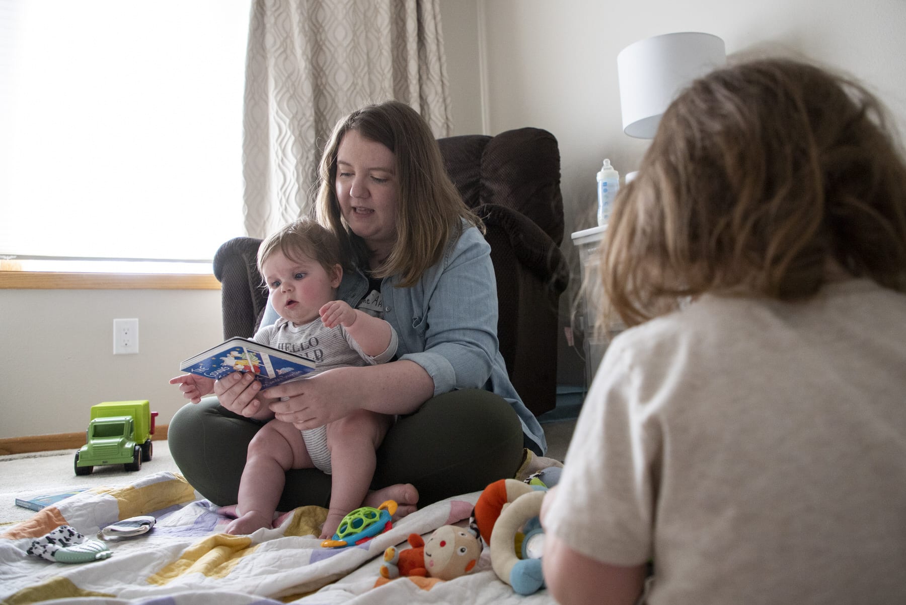 A mother reads to her children in a room.