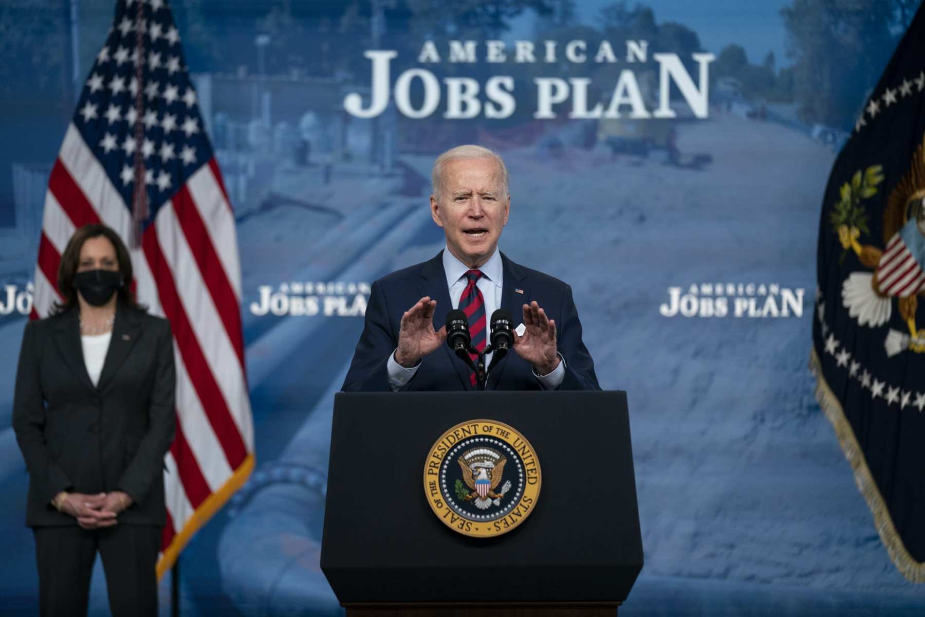 Joe Biden speaking at a podium in front of a backdrop that reads 