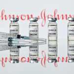 An illustration picture shows vials with Covid-19 Vaccine stickers attached and syringes with the Johnson & Johnson logo.