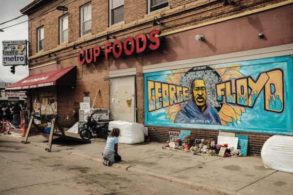 A woman pays respect to a mural of George Floyd by the Cup Foods storefront.