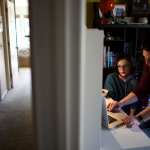 A mother helps her daughter with online classes in their home.