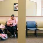 A woman fills out paperwork prior to a checkup with her 5-day old daughter.