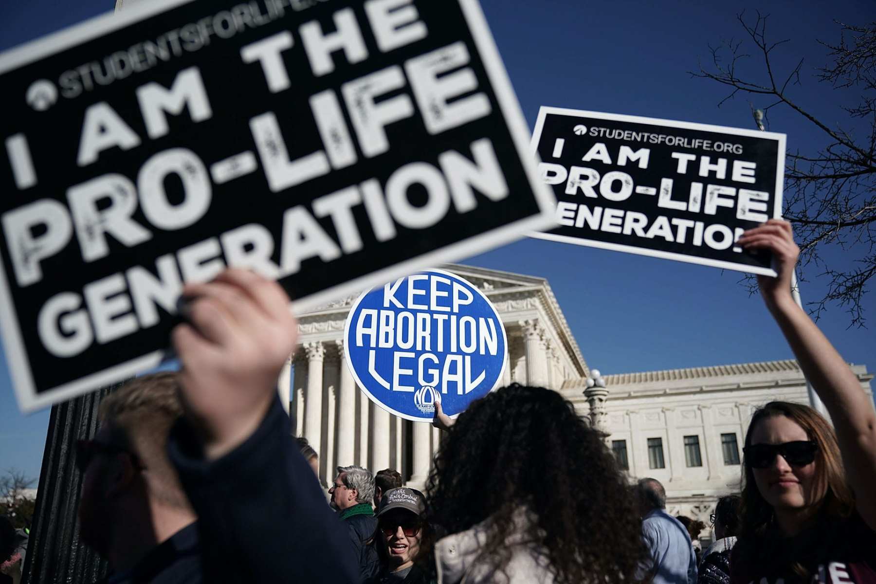 Protesters hold anti-abortion and abortion-rights signs in front of the Supreme Court.