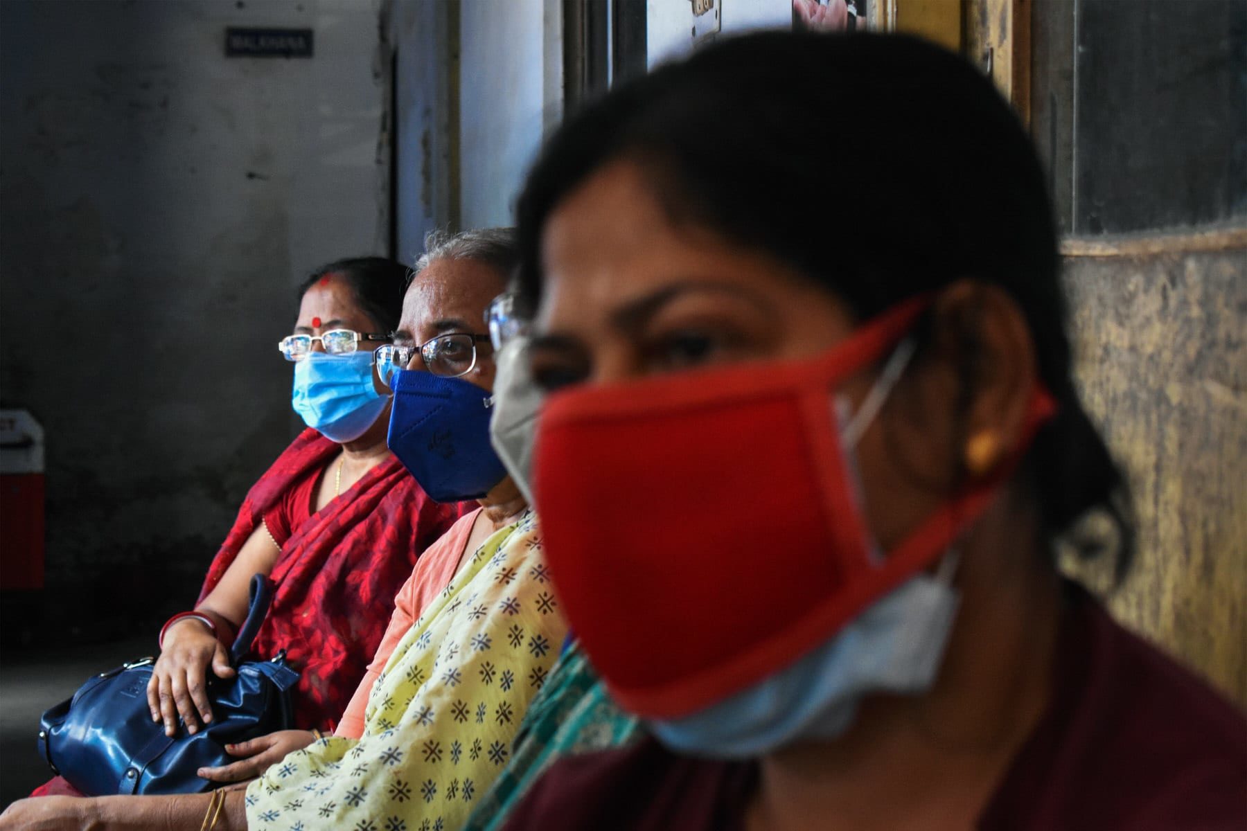 Women are wearing protective masks and waiting outside a covid-19 vaccination center.